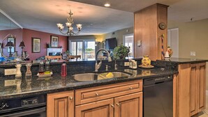 A modern kitchen with granite countertops, wooden cabinets, a double sink, and a dishwasher.