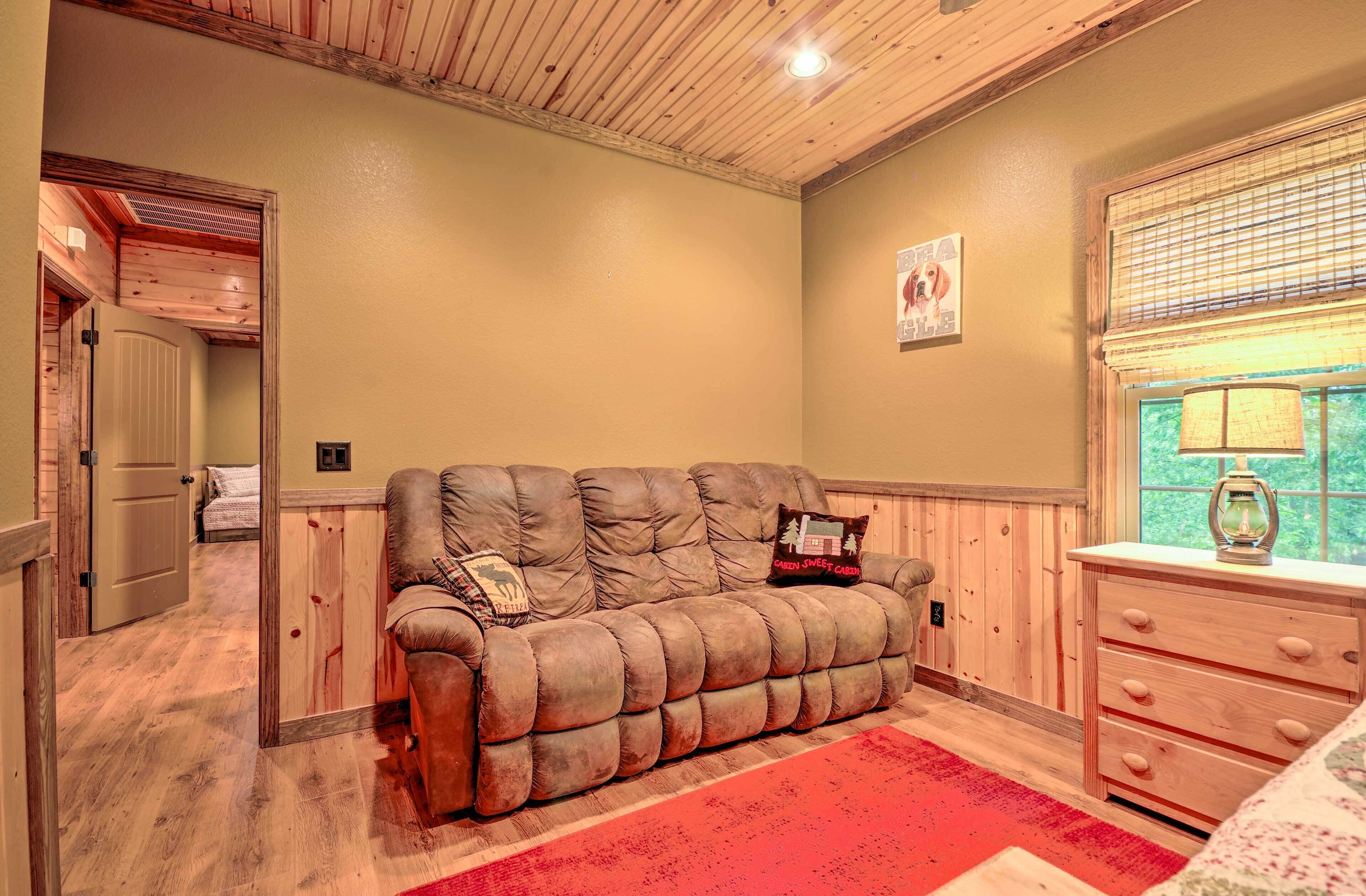 Um quarto aconchegante com um sofá marrom, um aparador de madeira e um tapete vermelho.