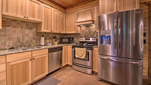 Une cuisine moderne avec des meubles en bois, des appareils électroménagers en acier inoxydable et un plan de travail en granit.