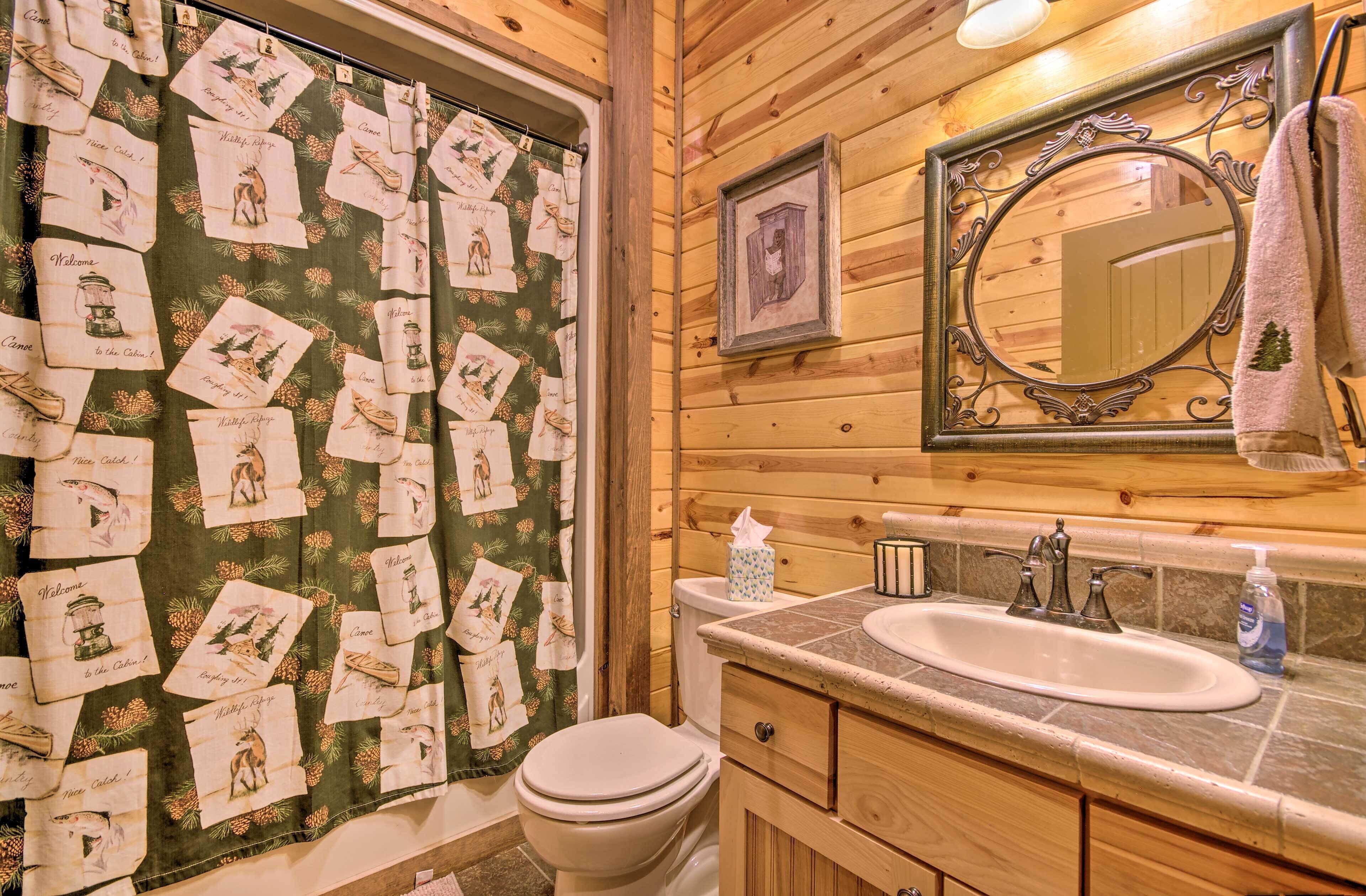 A bathroom with a wooden interior, a toilet, a sink with a mirror above it, and a towel hanging on the wall.