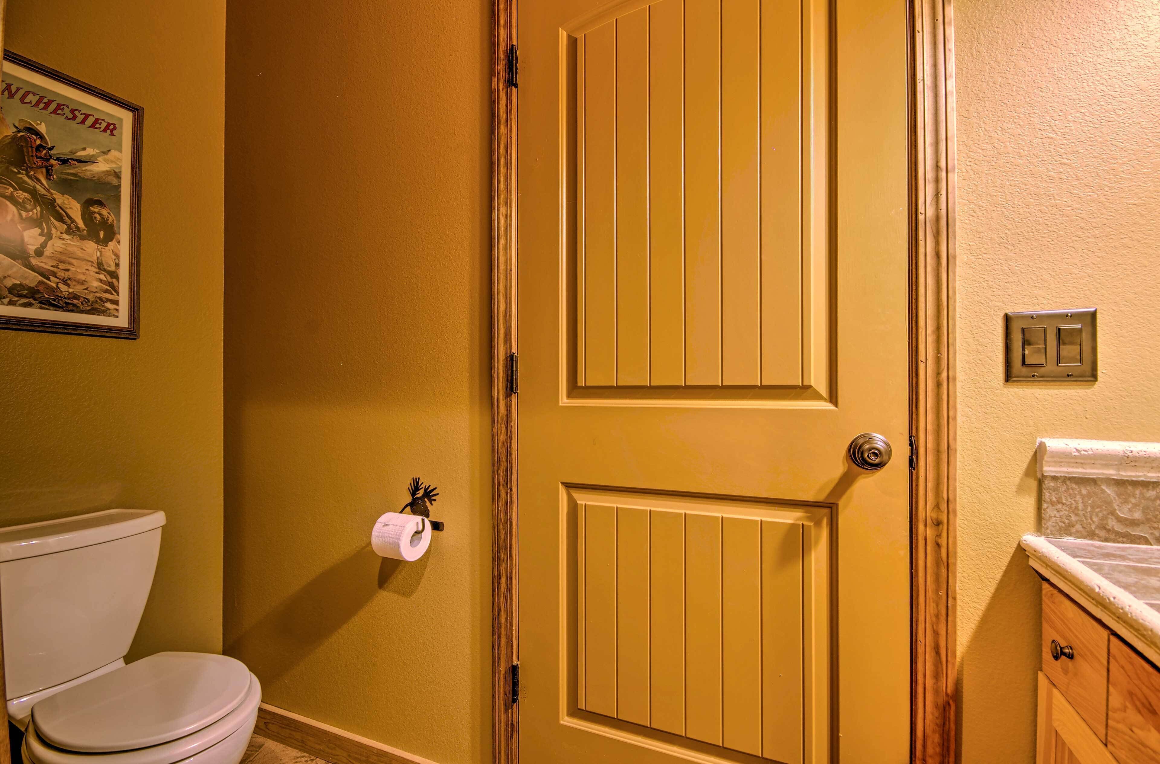 Un baño con un inodoro, una puerta y un cartel en la pared.