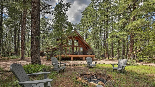 A cabin surrounded by tall pine trees, with Adirondack chairs arranged around a fire pit. - Pinetop Chalet Cabin ~ 1 Mi to Woodland Park (Pinetop)