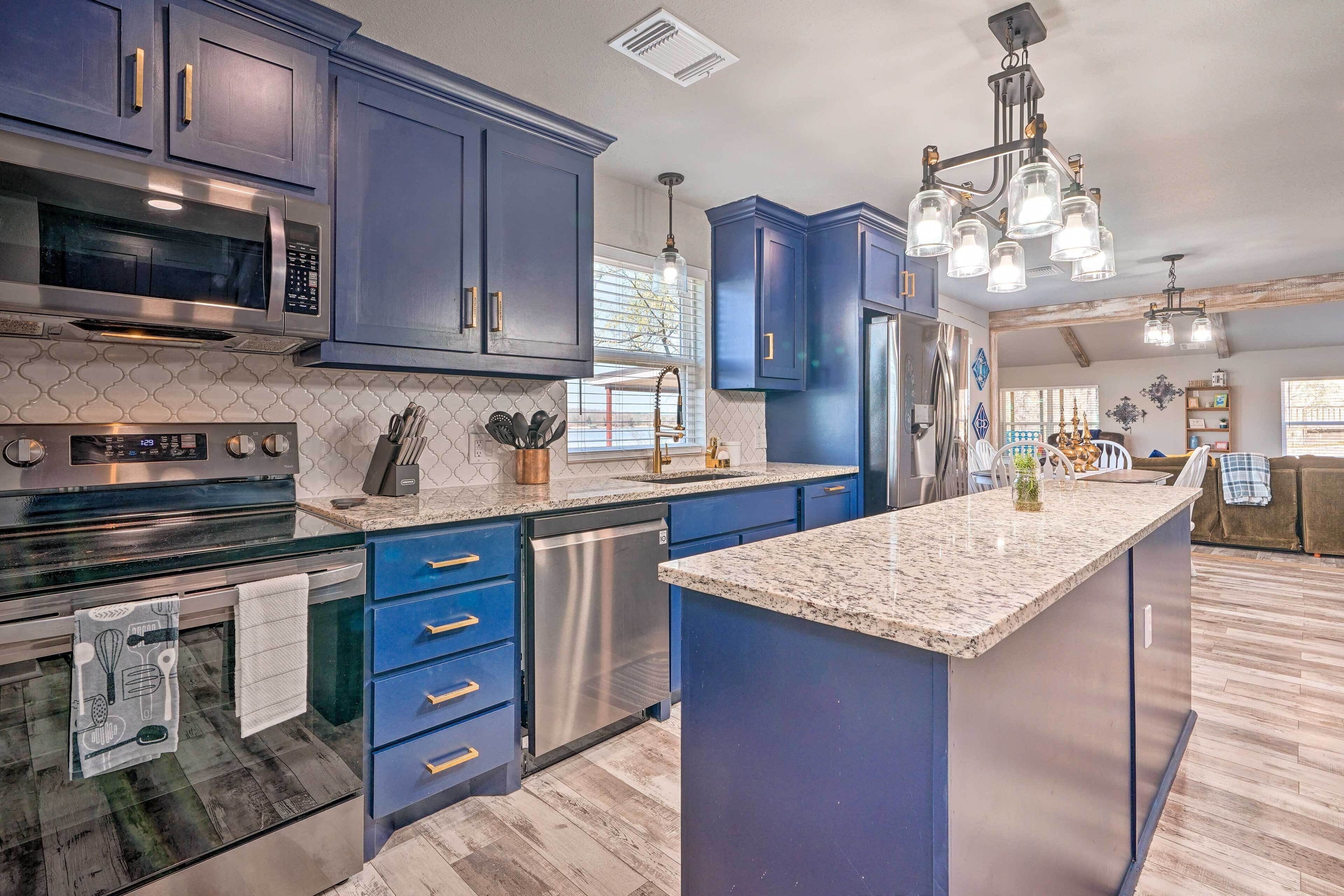 A modern kitchen with dark blue cabinets, stainless steel appliances, and a granite countertop.