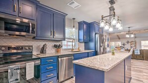 A modern kitchen with dark blue cabinets, stainless steel appliances, and a granite countertop. - Lakefront Fort Towson Home: Private Dock & 3 Decks (Fort Towson)