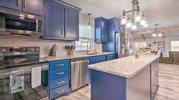 A modern kitchen with dark blue cabinets, stainless steel appliances, and a granite countertop.