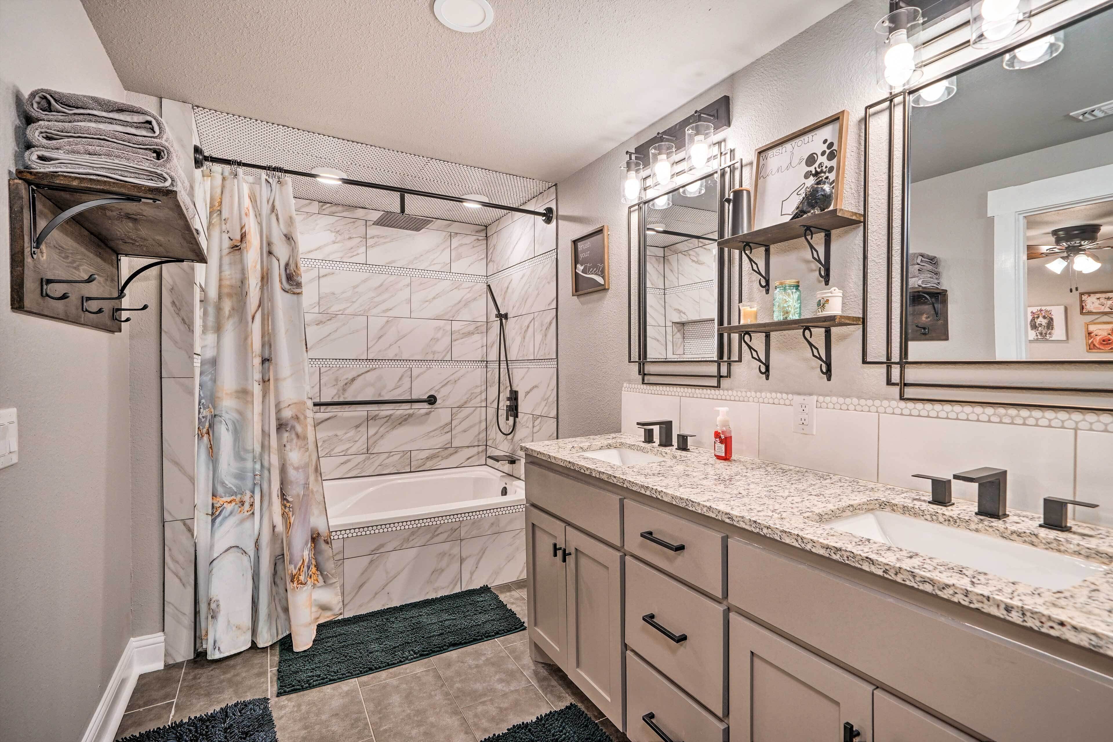 A modern bathroom with a marble shower, a large vanity with a sink, and a mirror above the sink.