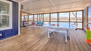 A covered outdoor area with a ping pong table, chairs, and a view of a lake. - Lakefront Fort Towson Home: Private Dock & 3 Decks (Fort Towson)