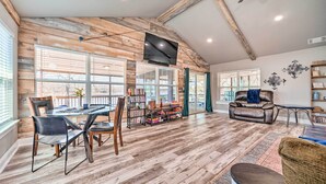 A spacious living area with a wooden ceiling, a dining table with chairs, a sofa, and a bookshelf. - Lakefront Fort Towson Home: Private Dock & 3 Decks (Fort Towson)