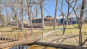 A wooden bridge over a small stream, leading to a building with a deck and a covered area. - Lakefront Fort Towson Home: Private Dock & 3 Decks (Fort Towson)