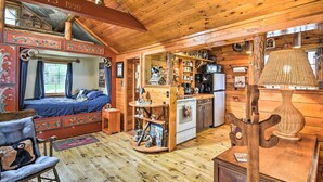 A cozy cabin interior with a bed, wooden walls, a kitchen area, and a dining table. - Cabin on Rush Lake w/ Bar, Grill & Kayaks! (Atlanta)