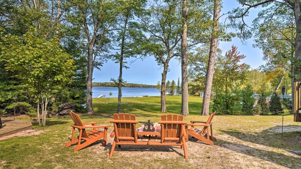 A wooden deck with Adirondack chairs and a table, overlooking a lake. - Cabin on Rush Lake w/ Bar, Grill & Kayaks! (Atlanta)