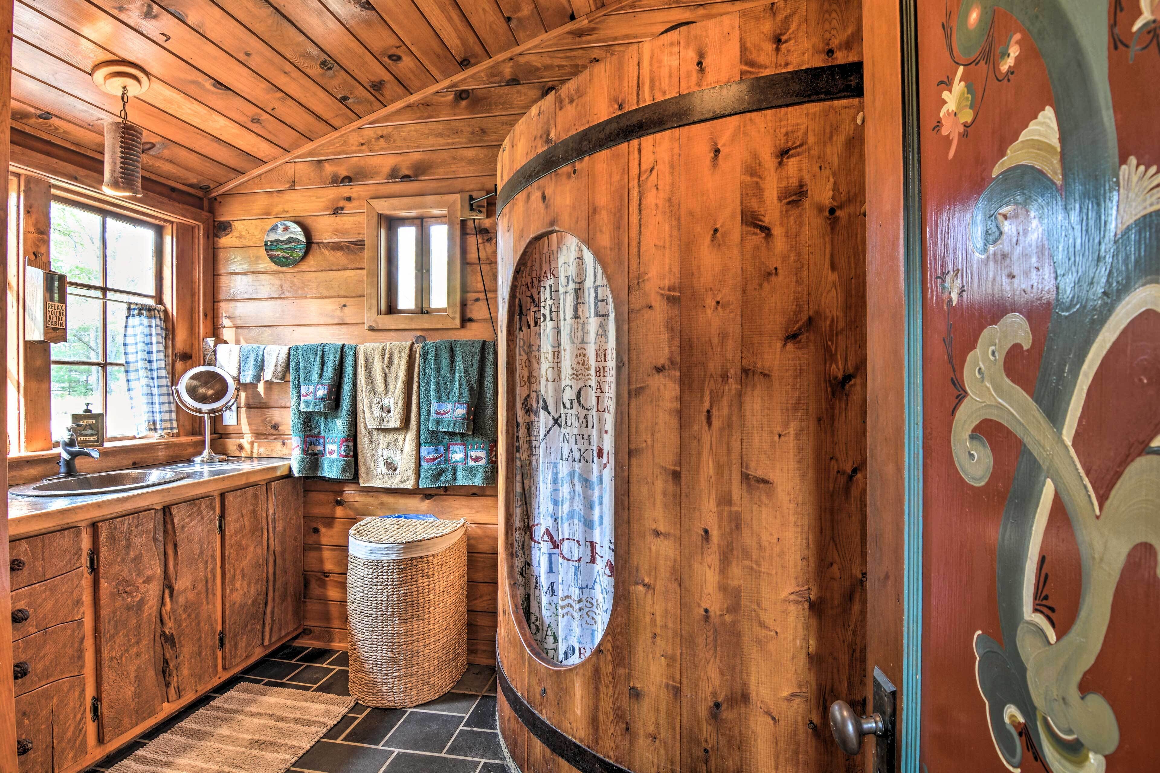 Interior de madera con cocina, que incluye un lavamanos, una cesta de mimbre y un perchero para toallas.