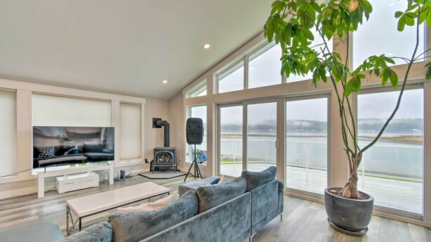 A modern living room with a large flat-screen TV, a sofa, a coffee table, and a potted plant. - Scenic & Spacious Getaway on North Bay w/ Deck! (Allyn)