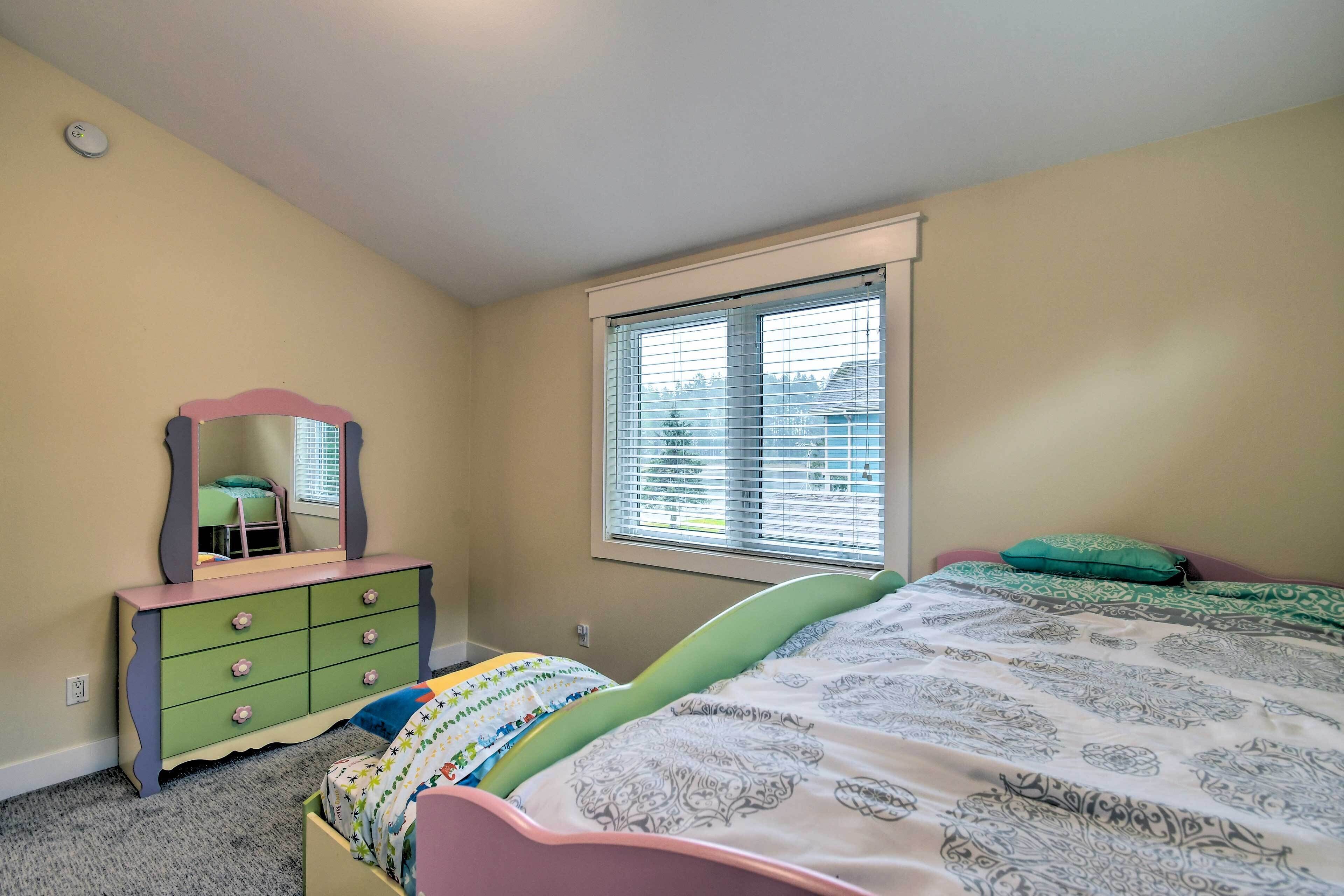 A bedroom with a bed, a dresser with a mirror, and a window with blinds.