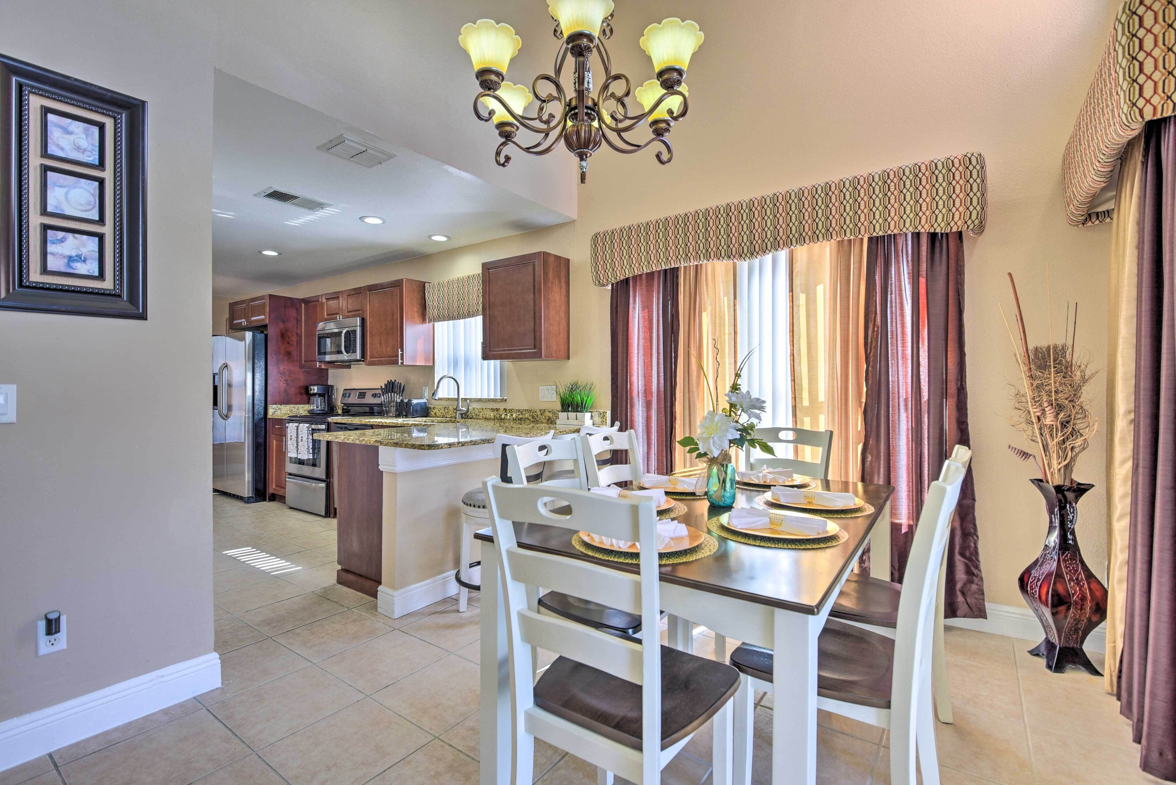 A spacious kitchen with modern appliances, a dining area with a chandelier, and a decorative vase.