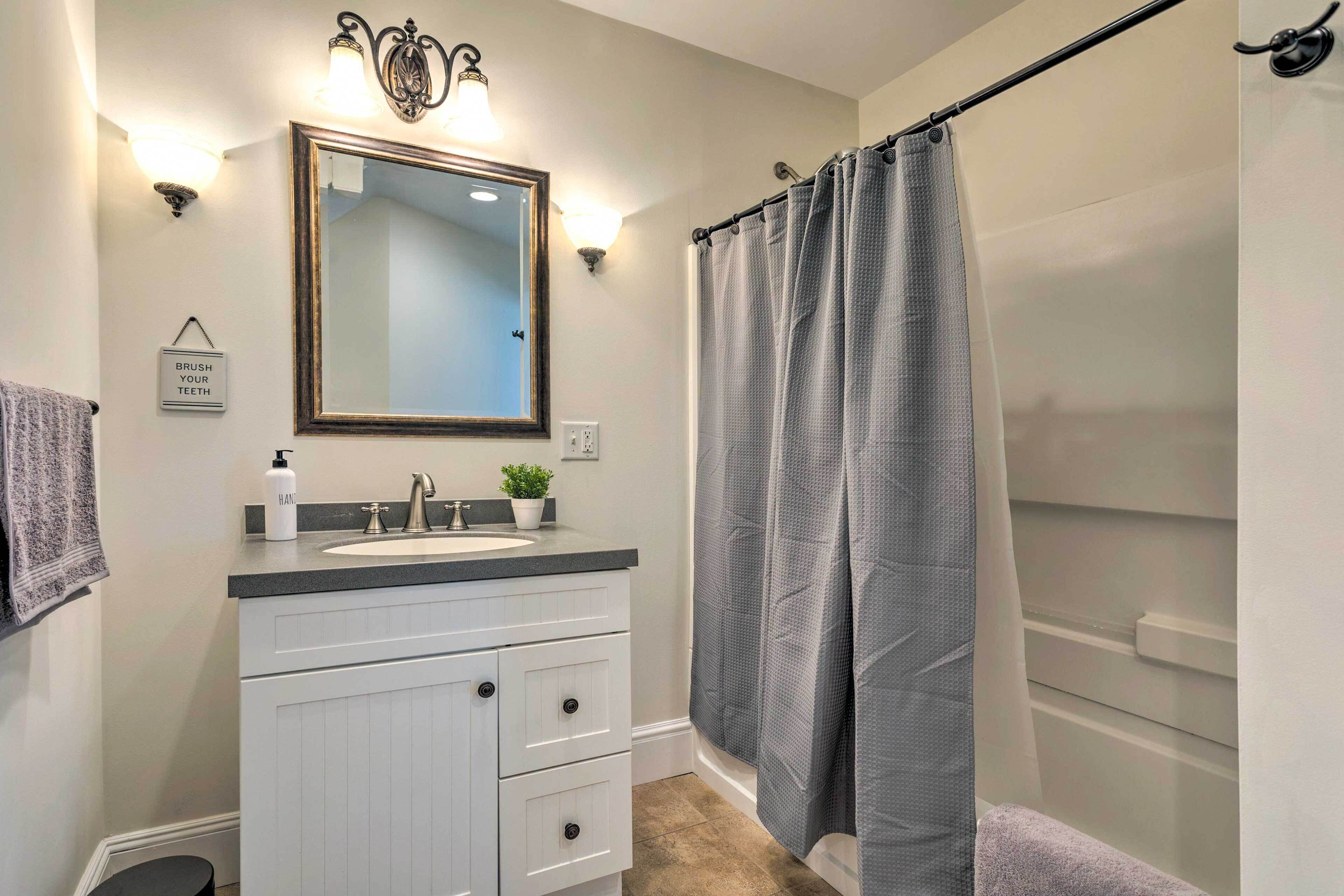 A bathroom with a sink, mirror, towel rack, and shower curtain.