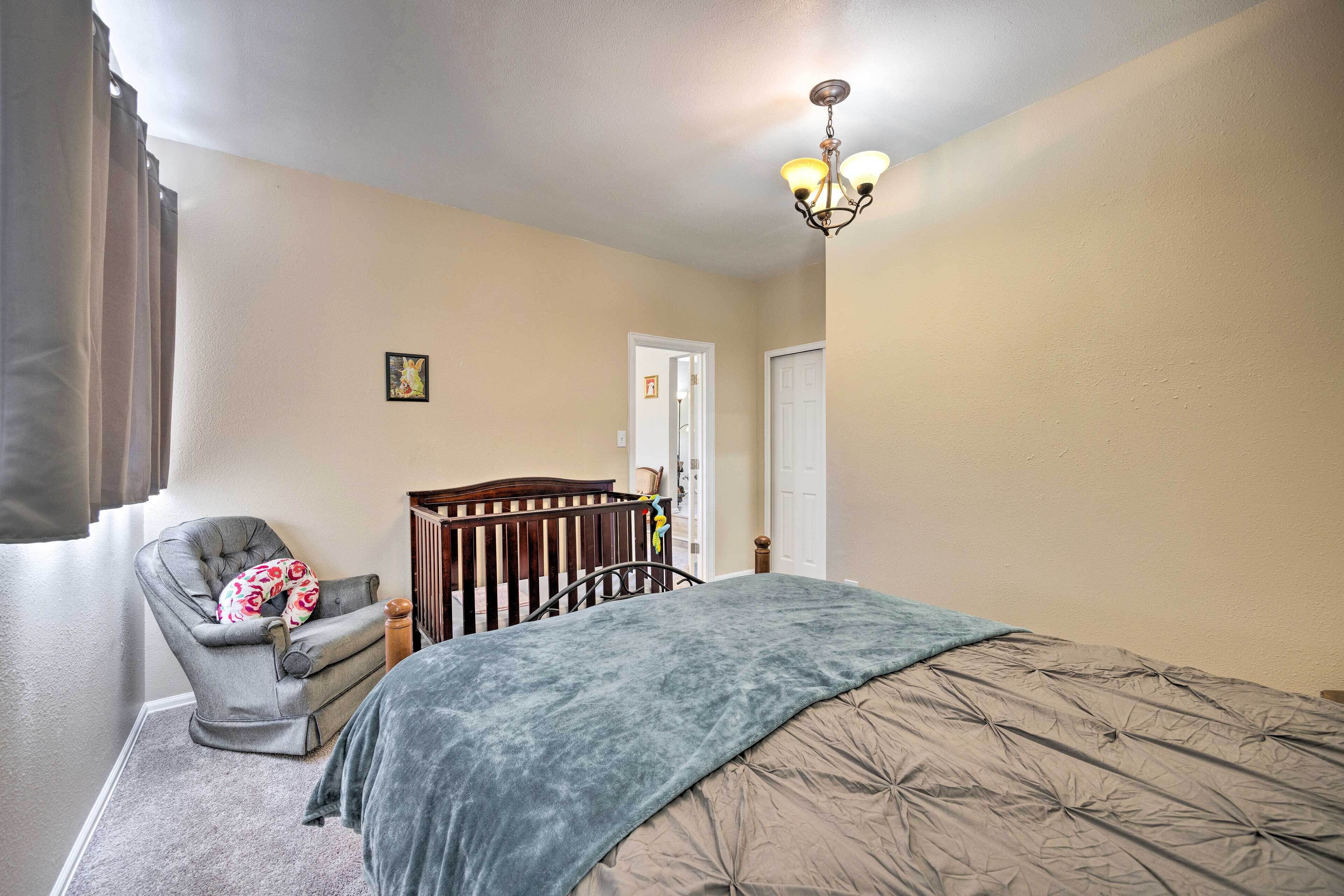 Un dormitorio con cama, una silla, una cuna y un candelabro.