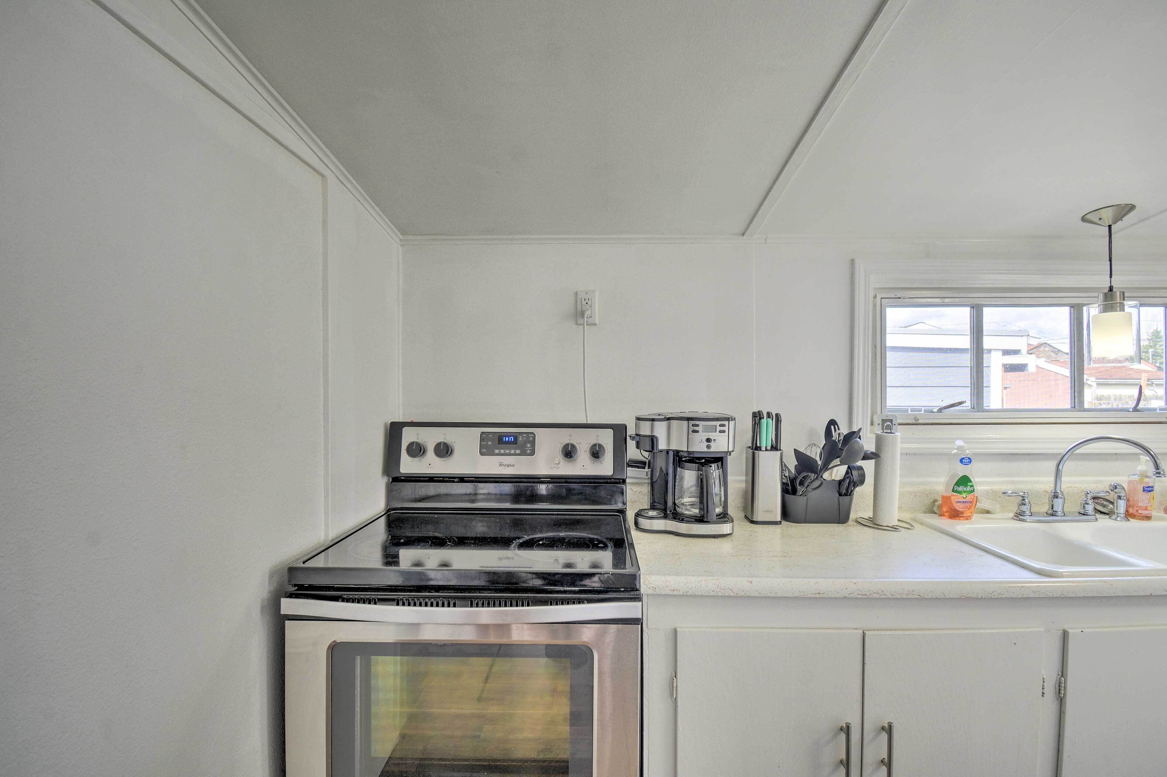 Cocina compacta con estufa, horno, cafetera y pileta con dispensadores de jabón.