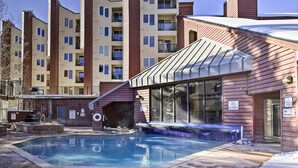Zona de piscina con jacuzzi, rodeada de edificios de apartamentos.