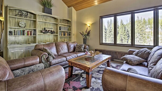 Una sala de estar acogedora con sofás de cuero, una mesa de centro de madera y una estantería llena de libros y objetos decorativos.