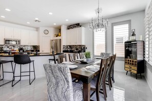 Una cocina moderna con armarios blancos, una isla central y un comedor con candelabro.