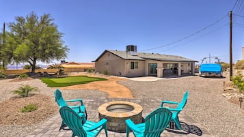 A house with a patio area featuring a fire pit and turquoise chairs.