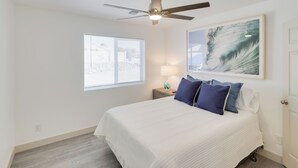 A bedroom with a bed, a ceiling fan, a window, a nightstand, a lamp, and a painting. - Putting Green, Pool Access: Lake Havasu City Home! (Lake Havasu City)