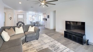 A modern living room with a sectional sofa, a flat-screen TV, and a ceiling fan. - Putting Green, Pool Access: Lake Havasu City Home! (Lake Havasu City)