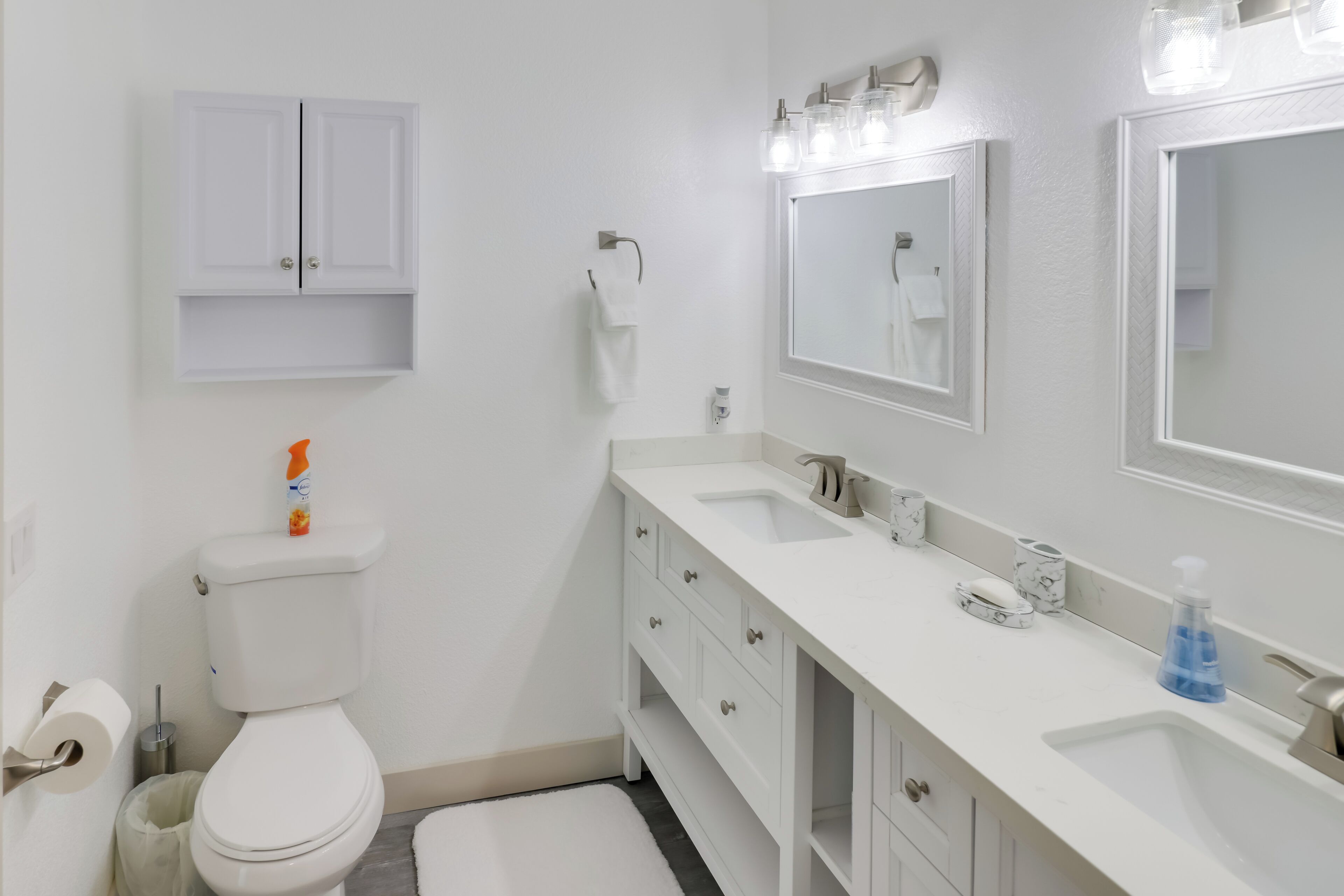 Une salle de bain équipée de toilettes, d’un lavabo, d’un meuble-lavabo et de miroirs.