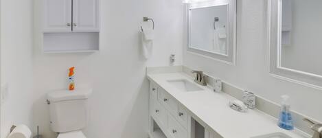 Une salle de bain équipée de toilettes, d’un lavabo, d’un meuble-lavabo et de miroirs.