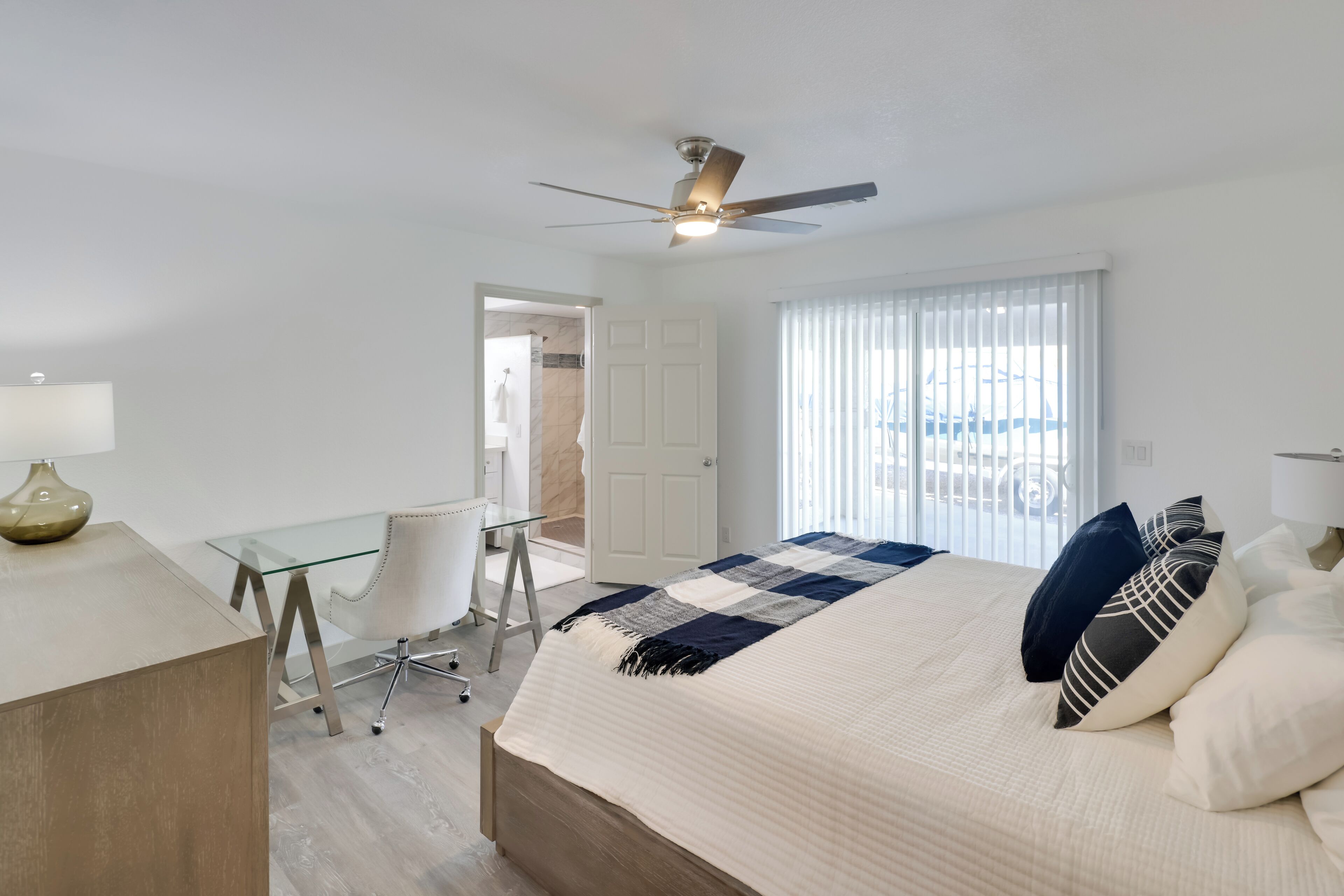 A modern hotel room with a bed, desk, and chair.