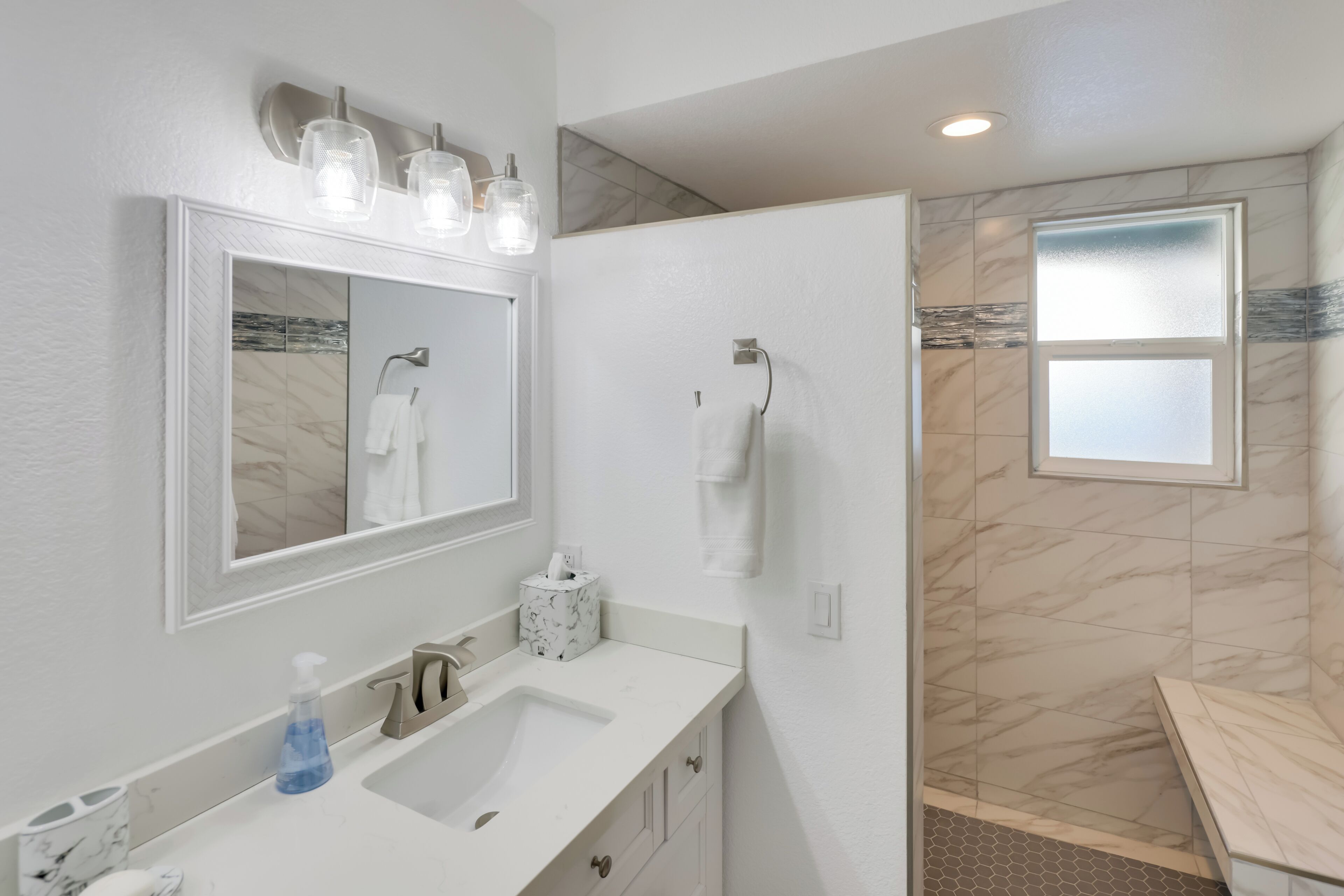 Un baño moderno con un espejo grande, un lavabo y una zona de ducha.