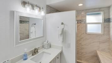 Un baño moderno con un espejo grande, un lavabo y una zona de ducha.