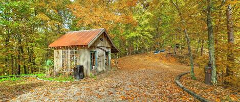 A rustic cabin surrounded by autumn foliage, with a gravel path leading to it.