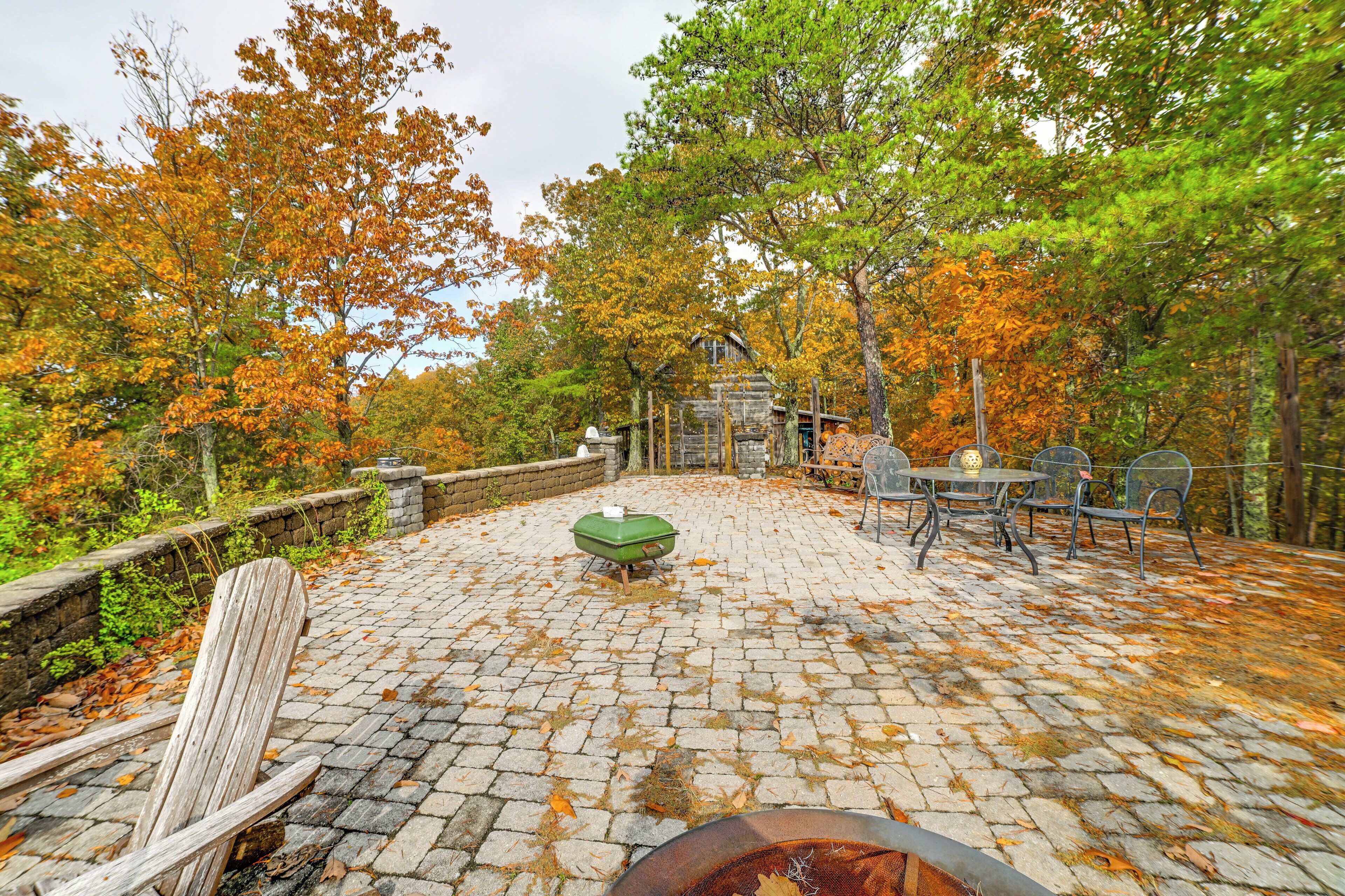 A stone patio with a fire pit, outdoor seating, and a wooden chair.