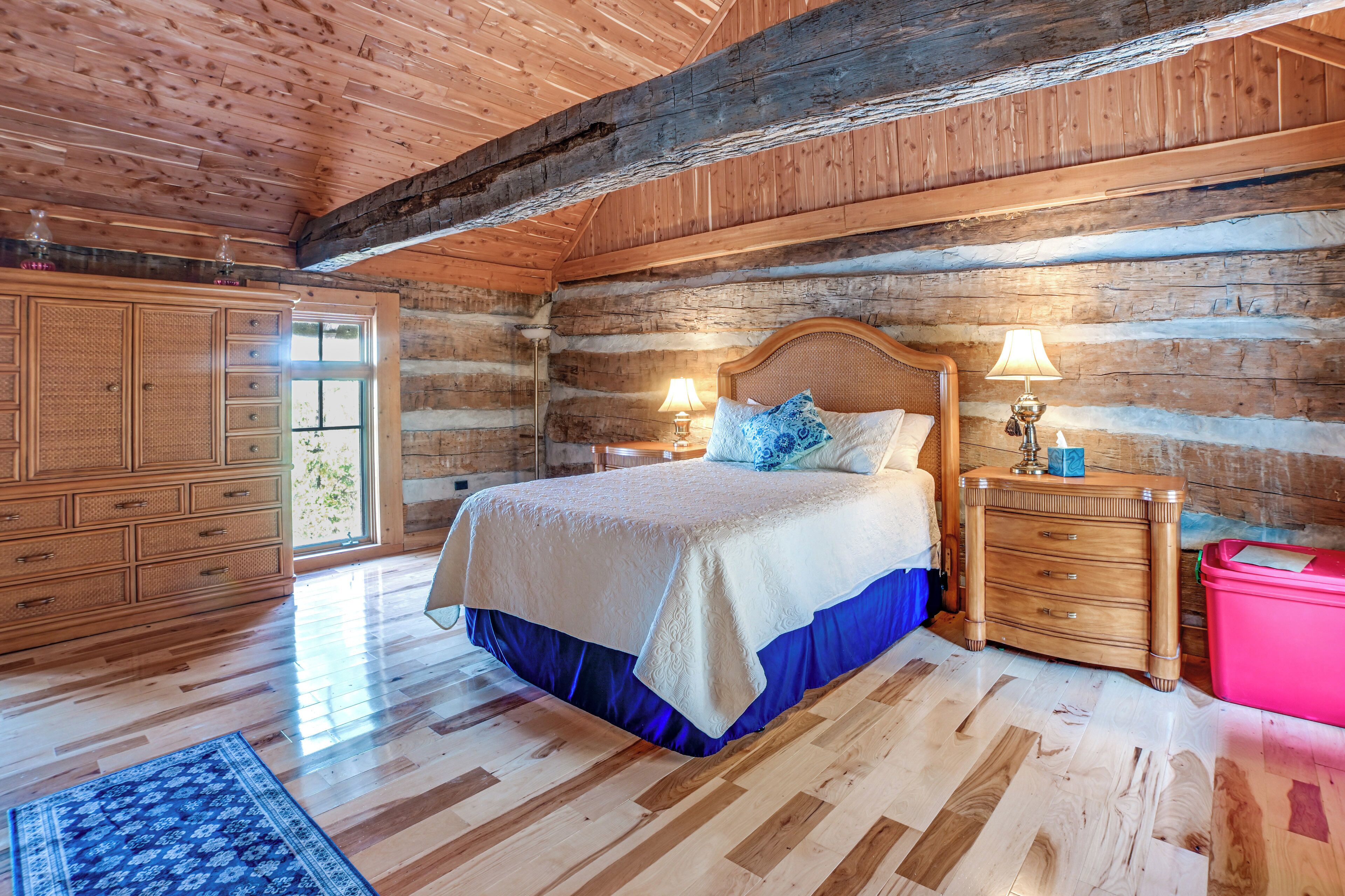 Un dormitorio tipo cabaña de madera con una cama grande, un aparador de madera y una ventana.