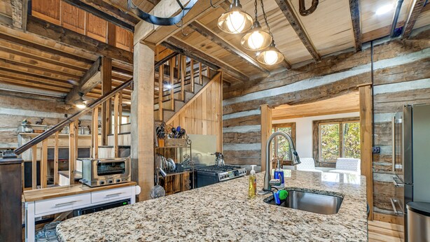 Eine Kücheneinrichtung im Chalet-Stil mit Granitarbeitsplatten, einem eingebauten Ofen und einer Spüle aus Edelstahl.