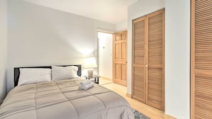 A bedroom with a bed, a nightstand, a lamp, and a wooden wardrobe.