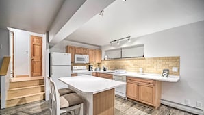A modern kitchen with a central island, wooden cabinets, and a microwave.