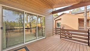 Une terrasse en bois avec un paillasson, une porte vitrée et une clôture en bois.