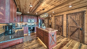 A rustic kitchen with wooden cabinets, a central island, and a farmhouse-style ceiling. - Galena Cabin w/ Wraparound Porch & Game Room! (Galena)