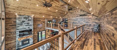 Une cabane spacieuse avec un intérieur en bois, une cheminée en pierre, un balcon et une terrasse en bois.