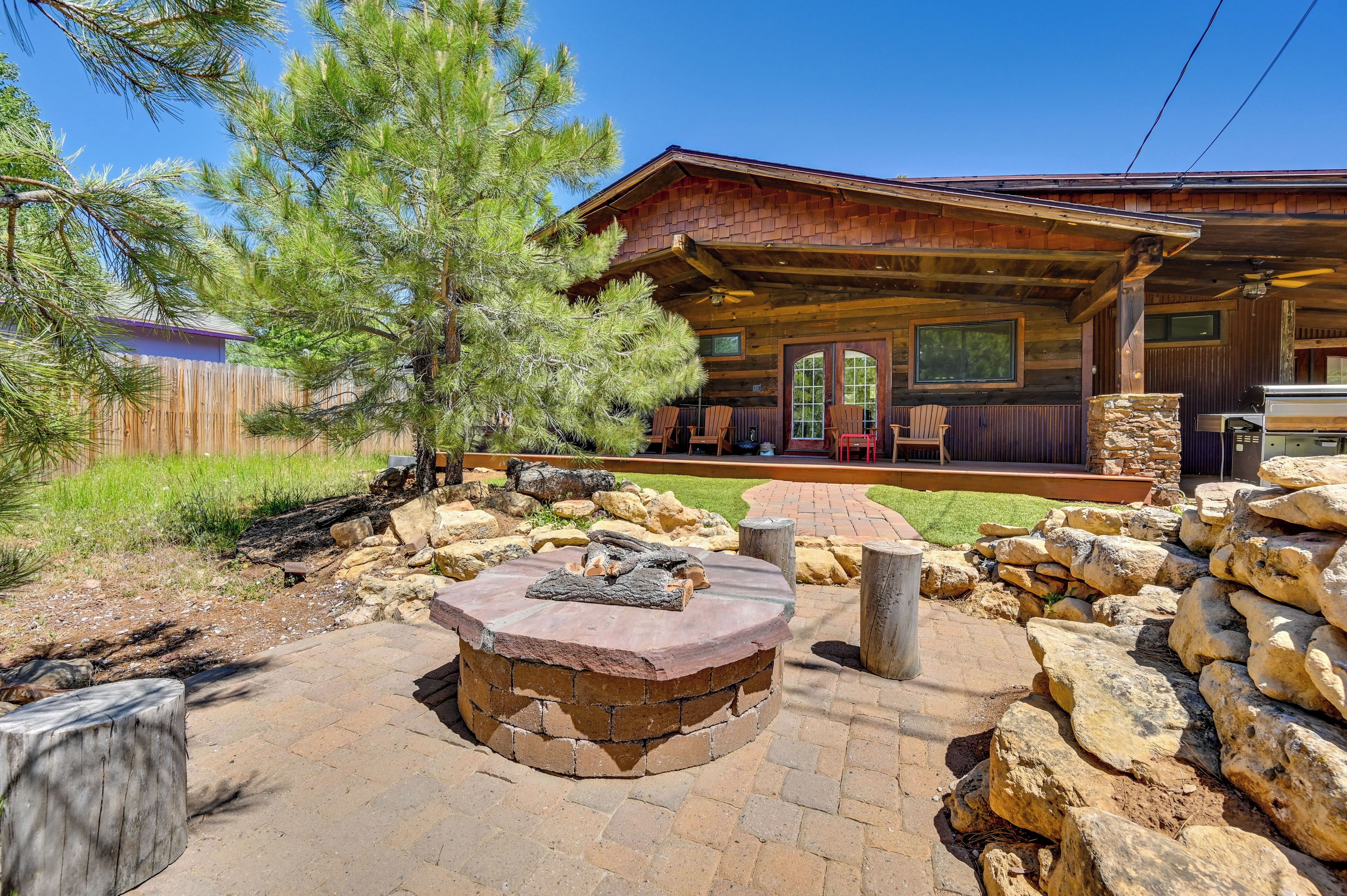 A rustic cabin with a stone fire pit, wooden deck, and a stone wall.