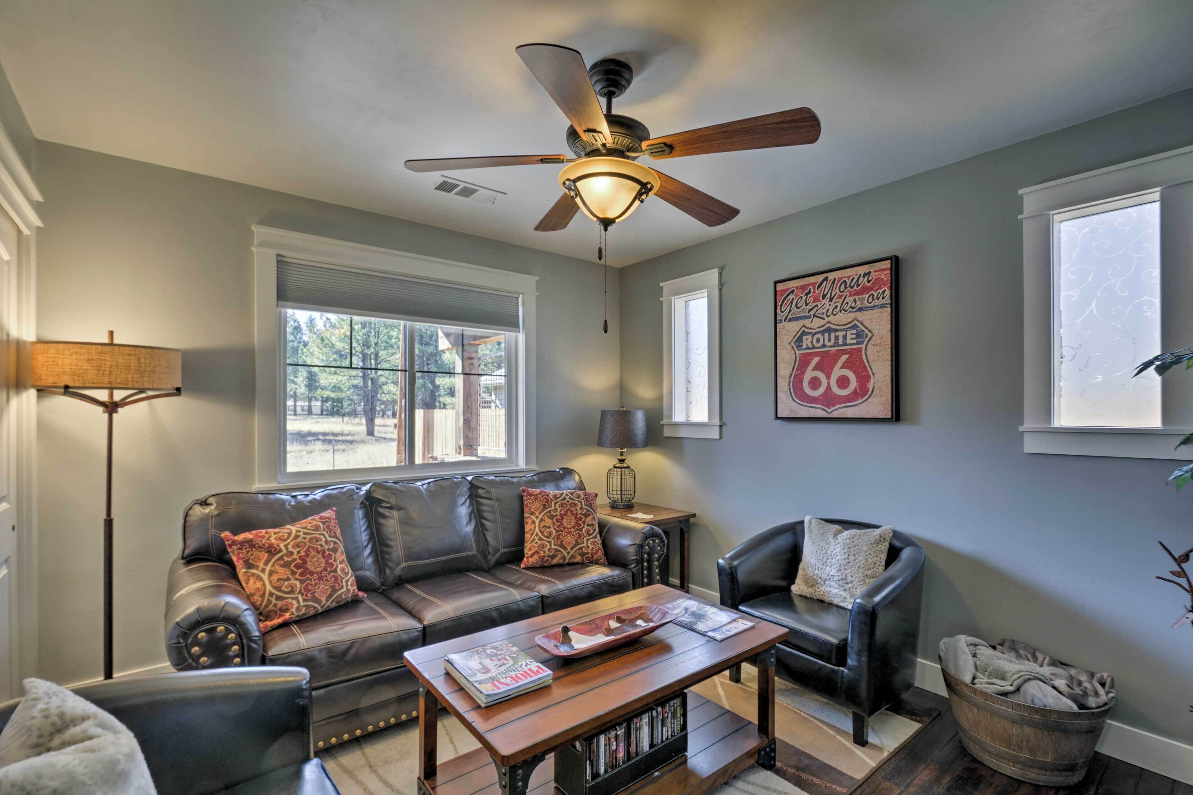 A living room with a ceiling fan, leather sofas, a coffee table, and a bookshelf.