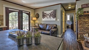 A spacious living area with a large window, a leather sofa, and a stone fireplace. - Home w/ Jacuzzi: 10 Mi to NAU & Flagstaff! (Flagstaff)