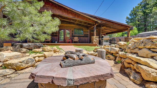 A rustic cabin with a covered porch, stone walls, and a fire pit in the foreground. - Home w/ Jacuzzi: 10 Mi to NAU & Flagstaff! (Flagstaff)