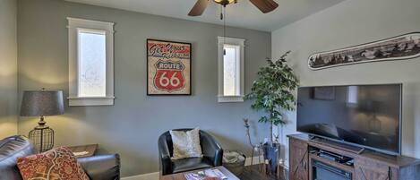 A living room with a ceiling fan, a television, a fireplace, and a Route 66 sign.