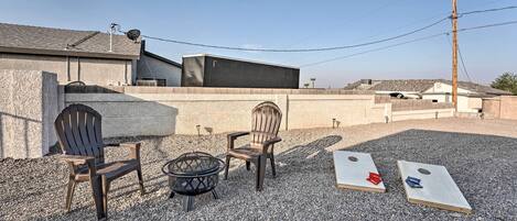 An outdoor seating area with two Adirondack chairs and a fire pit.
