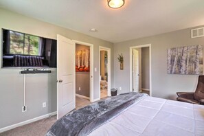 A bedroom with a large bed, a TV mounted on the wall, and a painting on the wall. - Mtn-view Home on 3 Acres w/ Arcade & Hot Tub! (Divide)