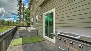 Um terraço com churrasqueira, móveis de exterior e vista para uma casa com porta de correr.